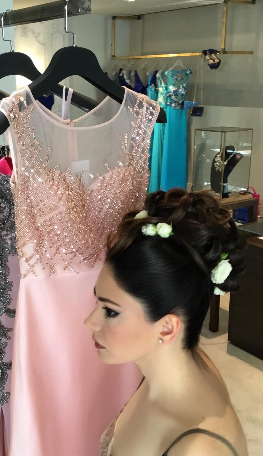 Raccolto alto scuro con roselline bianche, davanti agli abiti della boutique