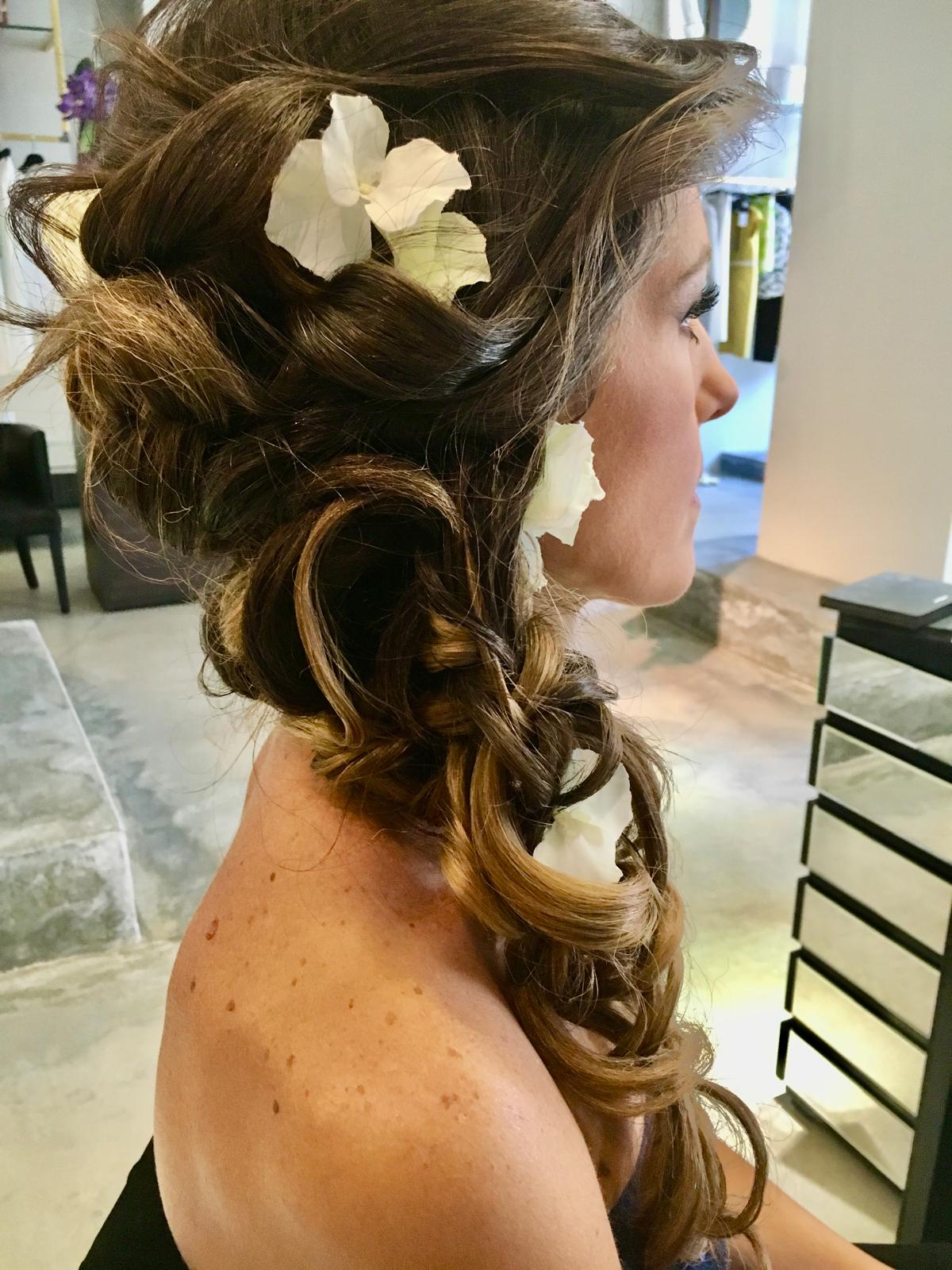 Acconciatura da sposa: raccolto morbido con boccoli e fiori bianchi tra i capelli